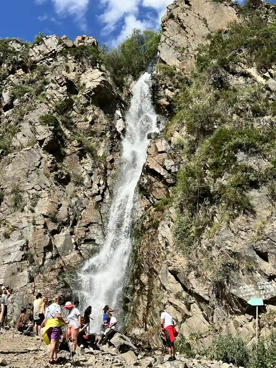 Tourists gathered at the base of Turgen waterfall cascading down a rocky cliff